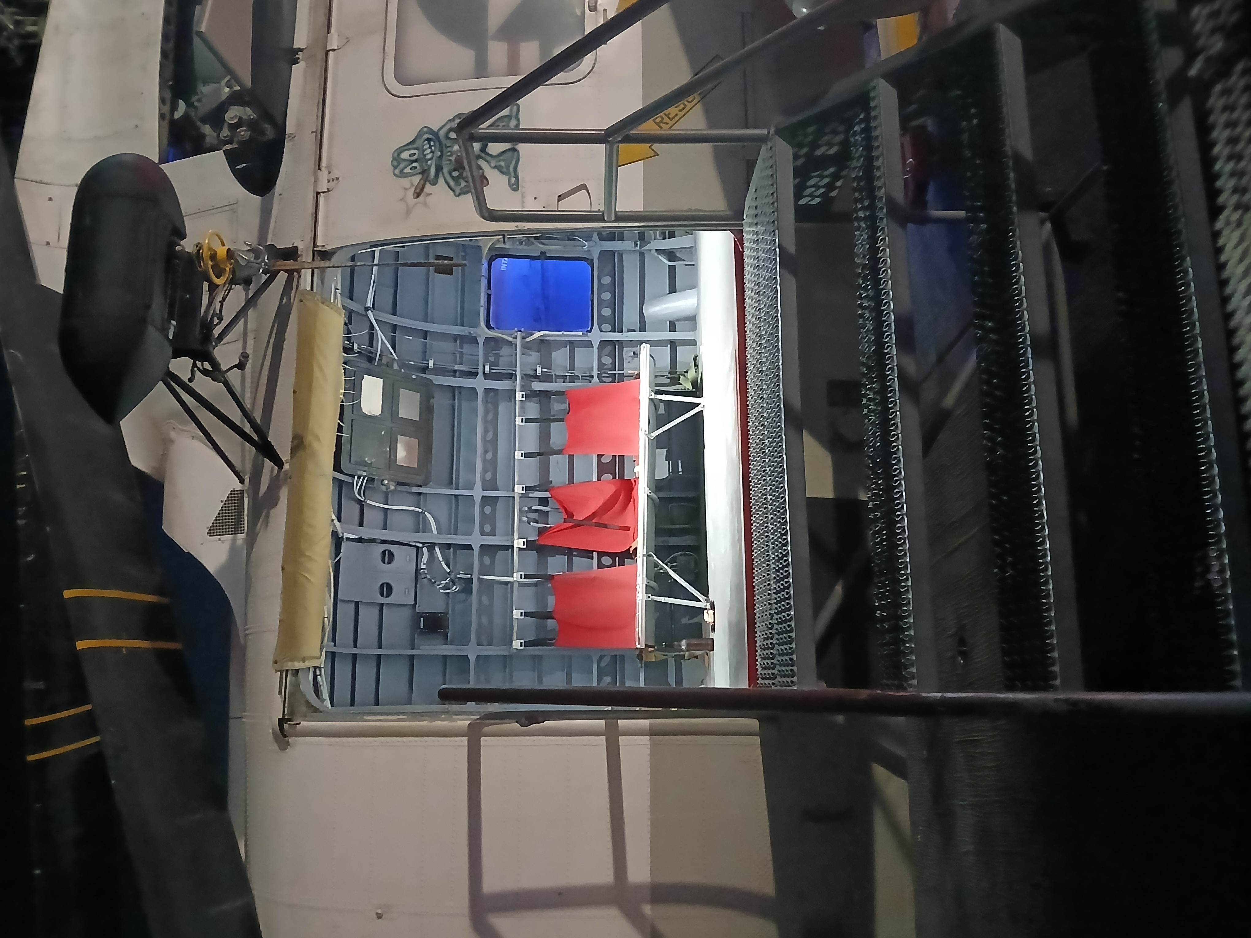 The interior of a rescue helicopter as pictured through the bay door on the side. A row of three benches stares out at the camera, and someone has left a slice of a dessert and a bottle of beer on the floor next to them.